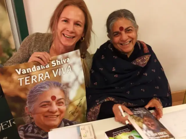 Right: Vanandana Shiva signing books and a poster for Bamboo Retreat Hotel. Left: Hotel co-founder Helen Kämpf Image